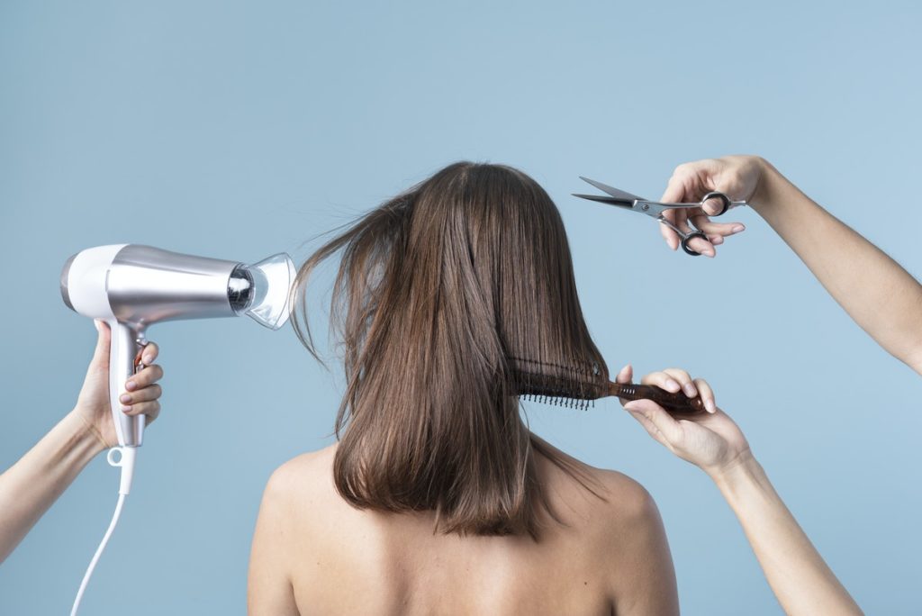 a womans hair is being cut and blow dried in a studio with blue background