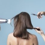 a womans hair is being cut and blow dried in a studio with blue background