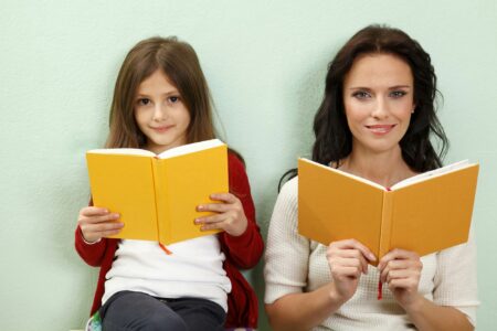 a portrait of a mother and daughter both reading their own book